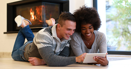 Image showing multiethnic couple using tablet computer on the floor