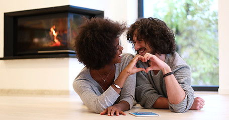 Image showing multiethnic couple showing a heart with their hands on the floor