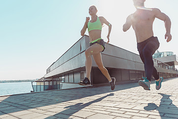 Image showing Pretty sporty woman and man jogging at city