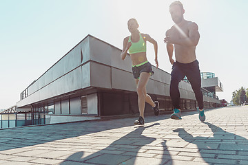 Image showing Pretty sporty woman and man jogging at city