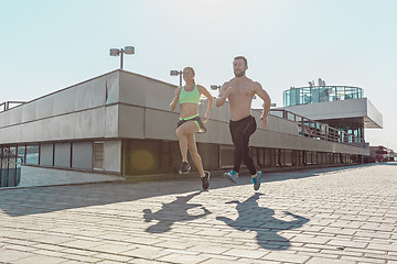 Image showing Pretty sporty woman and man jogging at city