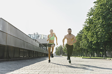 Image showing Pretty sporty woman and man jogging at city