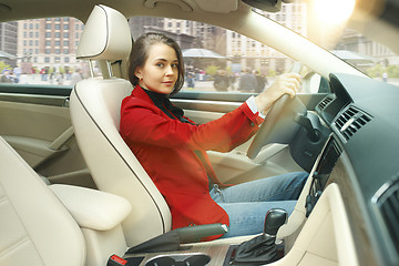 Image showing Driving around city. Young attractive woman driving a car