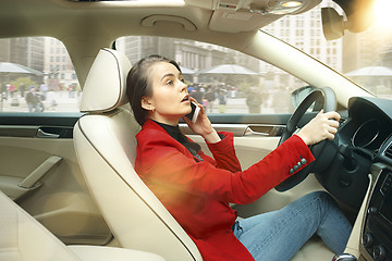 Image showing Driving around city. Young attractive woman driving a car