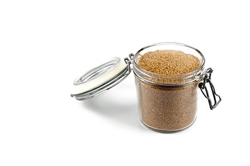 Image showing Brown cane sugar in glass jar isolated on white background.