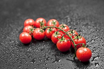 Image showing Fresh organic cherry tomatoes bunch closeup on black.