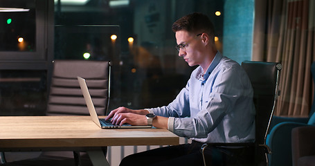 Image showing man working on laptop in dark office