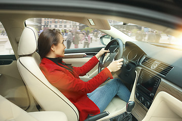 Image showing Driving around city. Young attractive woman driving a car