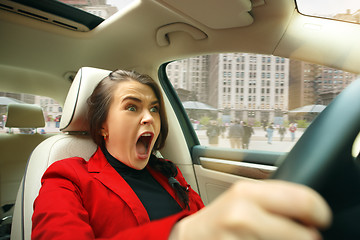 Image showing Driving around city. Young attractive woman driving a car