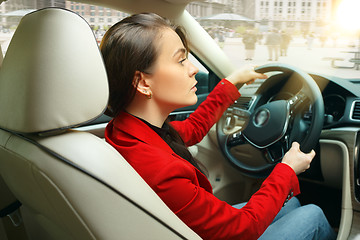 Image showing Driving around city. Young attractive woman driving a car