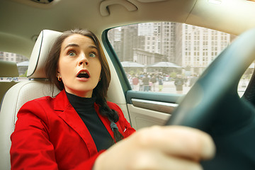 Image showing Driving around city. Young attractive woman driving a car