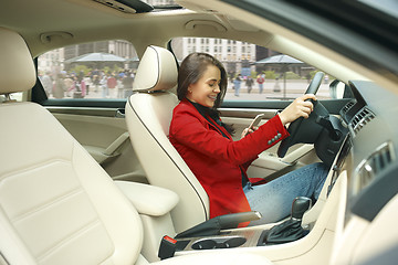 Image showing Driving around city. Young attractive woman driving a car