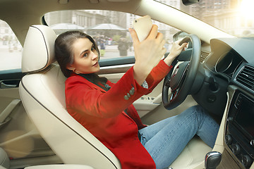 Image showing Driving around city. Young attractive woman driving a car