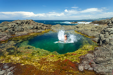 Image showing Woman making splash jumping into beautiful rock pool