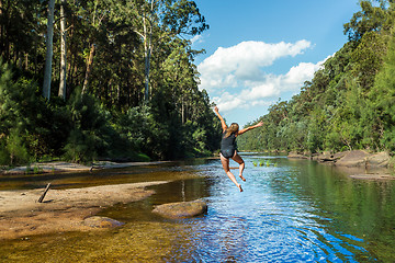 Image showing Active Aussie woman jumping into river remote bushland