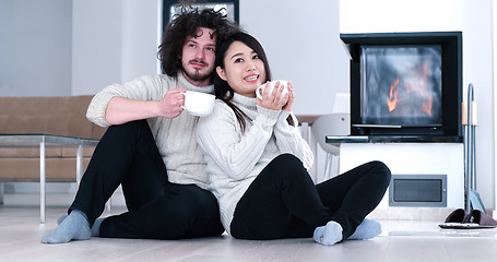 Image showing multiethnic romantic couple  in front of fireplace