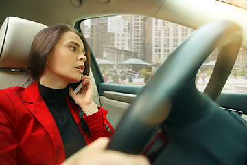 Image showing Driving around city. Young attractive woman driving a car