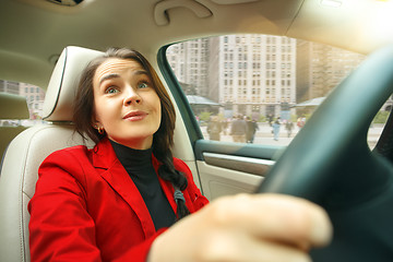 Image showing Driving around city. Young attractive woman driving a car