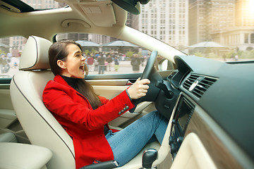 Image showing Driving around city. Young attractive woman driving a car