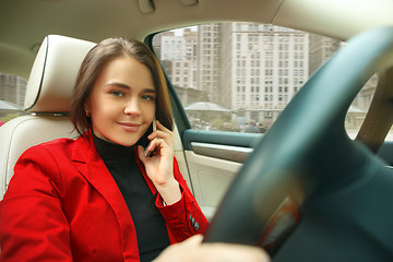 Image showing Driving around city. Young attractive woman driving a car