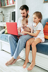 Image showing Proud father holding his baby daughters at home