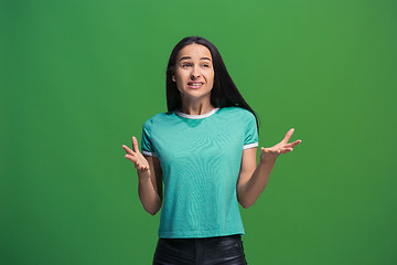 Image showing Beautiful female half-length portrait isolated on green studio backgroud. The young emotional surprised woman