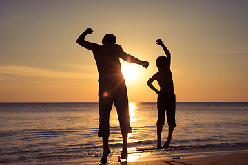 Image showing Father and son  playing on the beach at the sunset time.