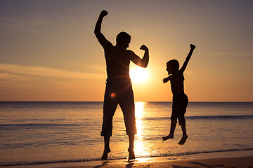 Image showing Father and son  playing on the beach at the sunset time.