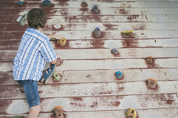 Image showing little boy climbing a rock wall outdoor.