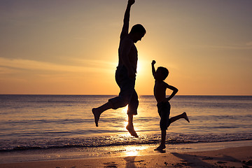 Image showing Father and son  playing on the beach at the sunset time.