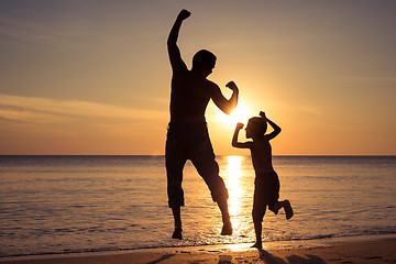 Image showing Father and son  playing on the beach at the sunset time.