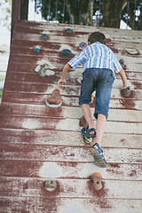 Image showing little boy climbing a rock wall outdoor.