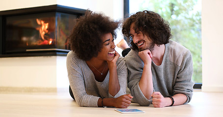 Image showing multiethnic couple lying on the floor  in front of fireplace