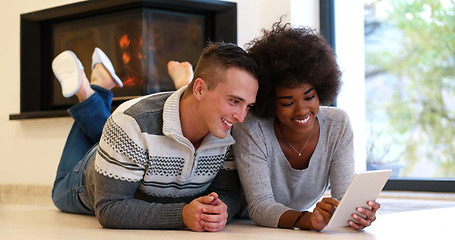 Image showing multiethnic couple using tablet computer on the floor