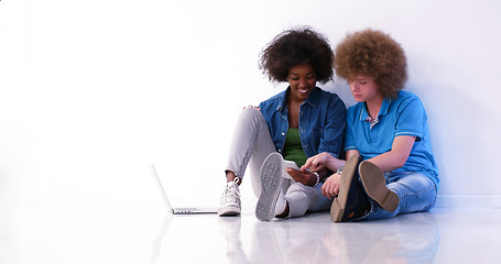 Image showing multiethnic couple sitting on the floor using a laptop and table