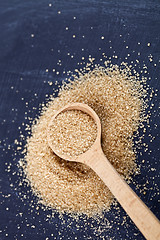 Image showing Brown cane sugar in wooden spoon on black board.