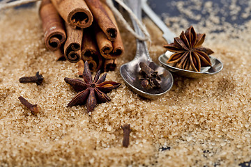 Image showing Brown cane sugar, cinnamon sticks and star anise closeup on blac