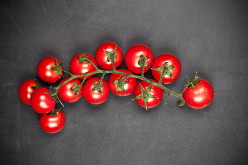 Image showing Fresh organic cherry tomatoes bunch closeup on black board backg