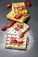 Image showing Belgium waffers with strawberries and sugar powder on black boar