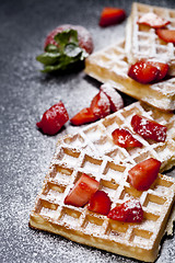 Image showing Belgium waffers with strawberries and sugar powder on black boar