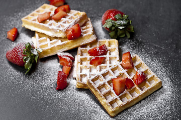 Image showing Belgium waffers with strawberries and sugar powder on black boar