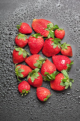 Image showing Fresh ripe strawberry with water drops on black background.