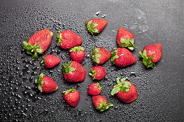 Image showing Fresh ripe strawberry with water drops on black background.