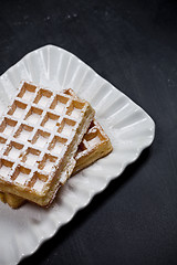 Image showing Belgium waffers with sugar powder on ceramic plateon black board