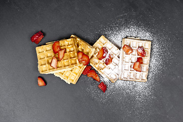 Image showing Belgium waffers with strawberries and sugar powder on black boar