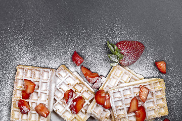 Image showing Belgium waffers with strawberries and sugar powder on black boar