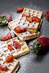 Image showing Belgium waffers with strawberries and sugar powder on black boar