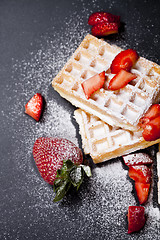 Image showing Belgium waffers with strawberries and sugar powder on black boar
