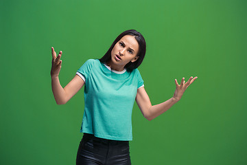 Image showing Beautiful female half-length portrait isolated on green studio backgroud. The young emotional surprised woman