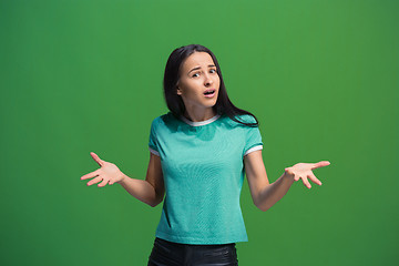 Image showing Beautiful female half-length portrait isolated on green studio backgroud. The young emotional surprised woman